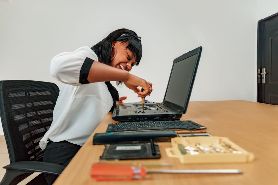Technician repairing a laptop at a workbench with tools